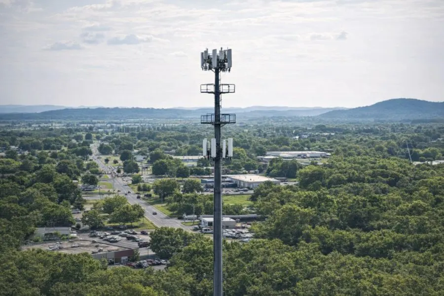 A telecommunications tower above a green community landscape
